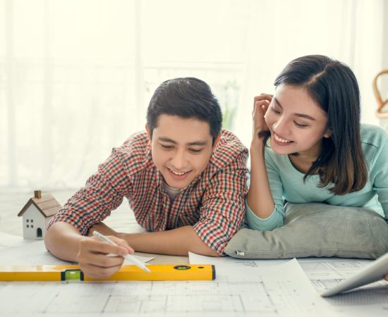 Close up of happy asian couple looking at blueprint at home