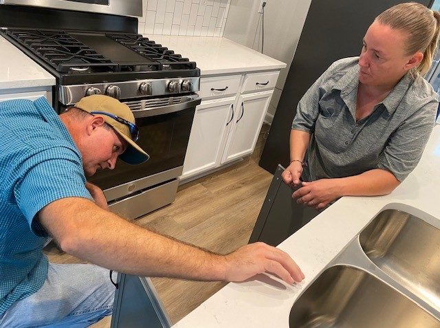 Homeowner lookin inside cabinets while the site builder talks